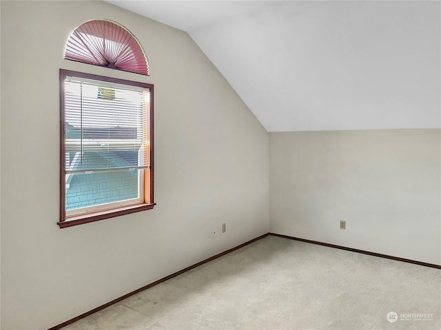 additional living space featuring vaulted ceiling and light carpet