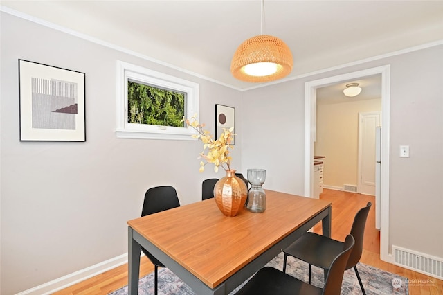 dining room featuring crown molding and light hardwood / wood-style floors