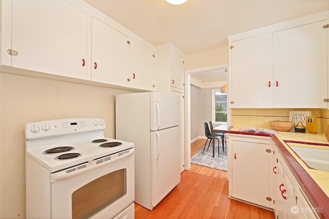 kitchen featuring white appliances, tile countertops, white cabinets, and light wood-type flooring