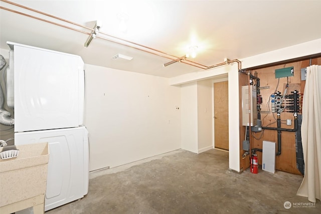 basement featuring stacked washer and clothes dryer and sink