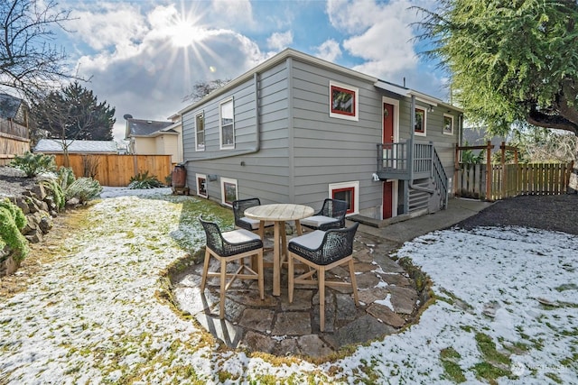 snow covered house featuring a patio area