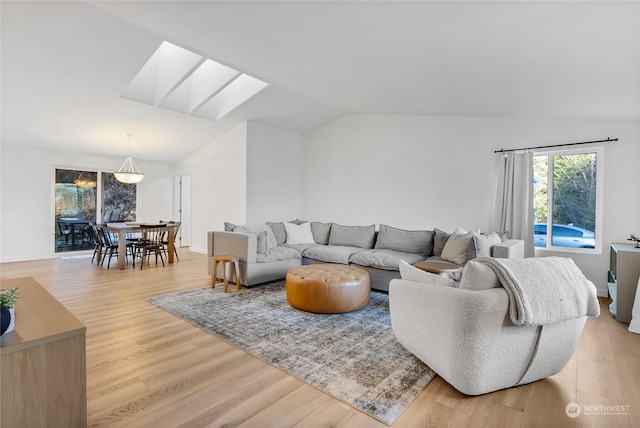 living room with vaulted ceiling with skylight and light wood-type flooring