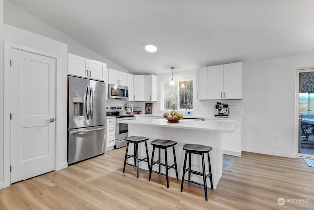 kitchen featuring appliances with stainless steel finishes, a kitchen breakfast bar, a kitchen island, pendant lighting, and white cabinets