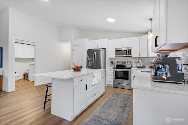 kitchen with lofted ceiling, white cabinetry, a kitchen island, pendant lighting, and stainless steel appliances