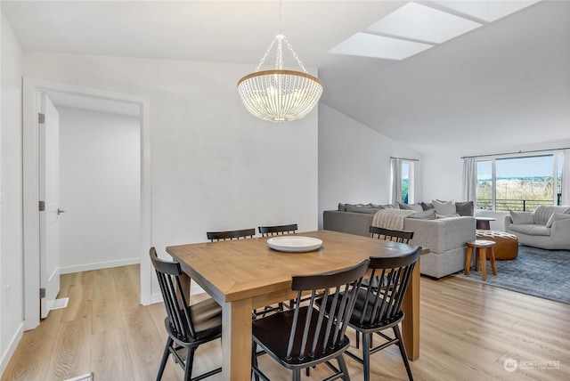 dining room featuring an inviting chandelier, lofted ceiling with skylight, and light hardwood / wood-style flooring