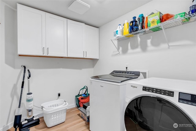 laundry area featuring separate washer and dryer, cabinets, and light wood-type flooring