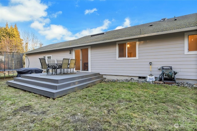 back of house with a trampoline, a yard, and a deck