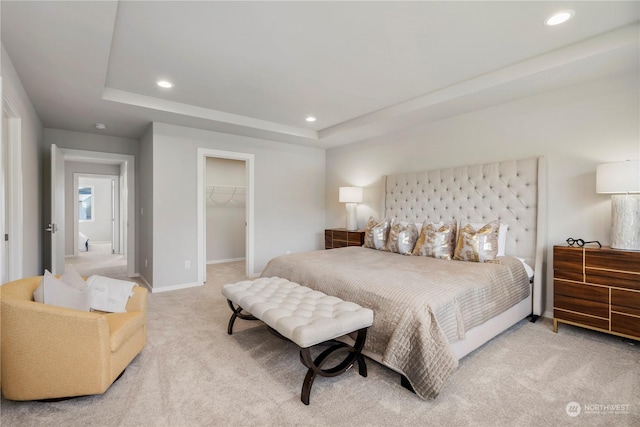 carpeted bedroom featuring a raised ceiling, a walk in closet, and a closet