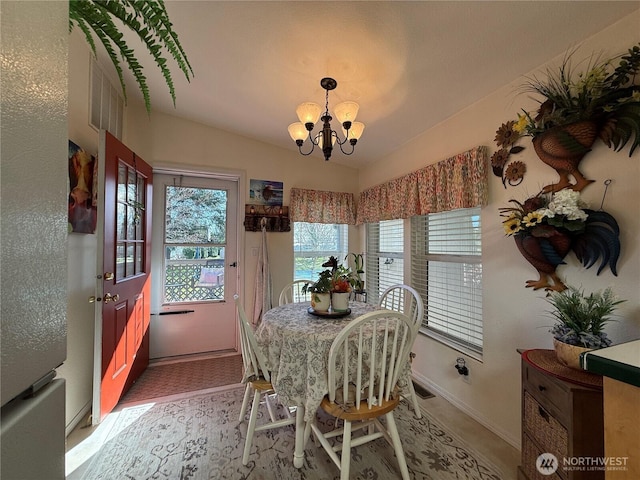 dining area with baseboards, vaulted ceiling, and a notable chandelier