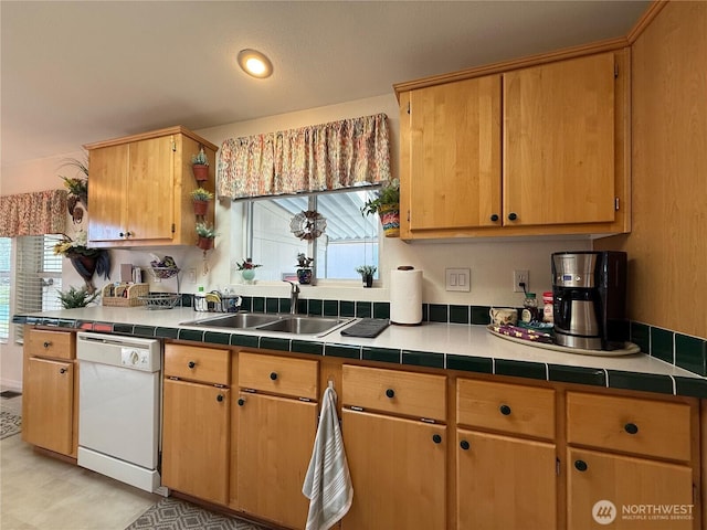 kitchen with tile countertops, white dishwasher, and a sink