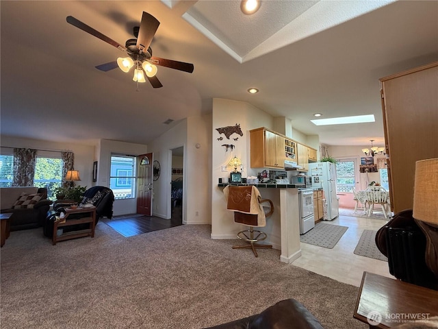 kitchen with tile countertops, a breakfast bar area, lofted ceiling, light colored carpet, and open floor plan