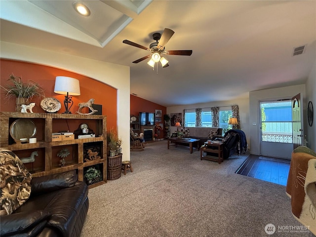 carpeted living area with visible vents, vaulted ceiling, and ceiling fan