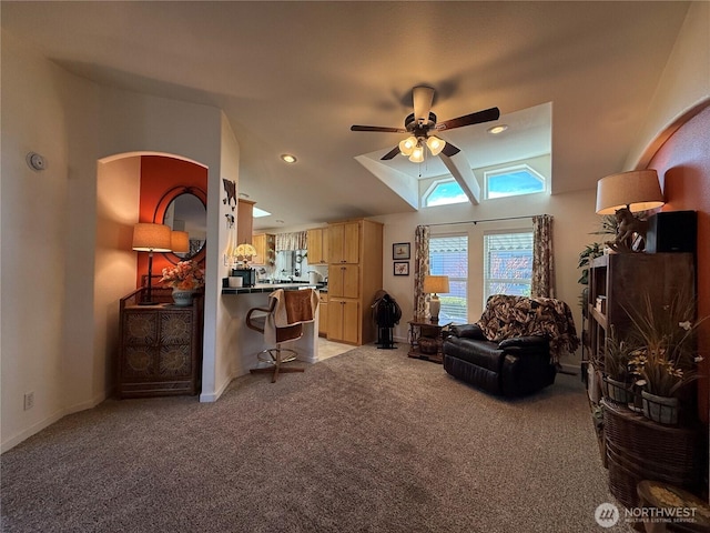 living room featuring lofted ceiling, ceiling fan, baseboards, and light colored carpet