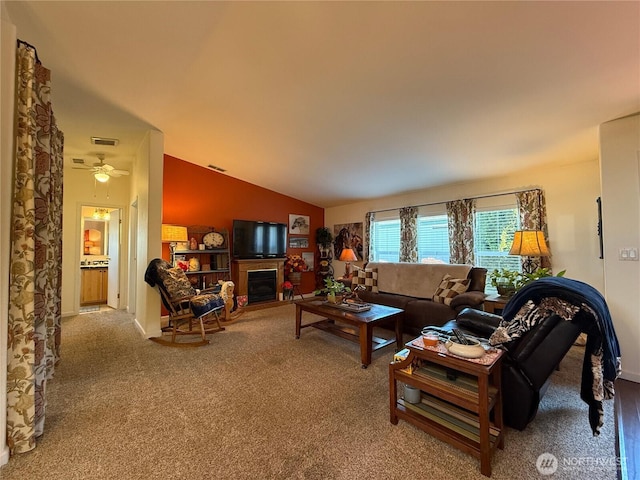 carpeted living room with lofted ceiling, ceiling fan, visible vents, and a glass covered fireplace