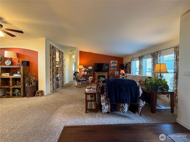 living room with vaulted ceiling, a fireplace, wood finished floors, and a ceiling fan