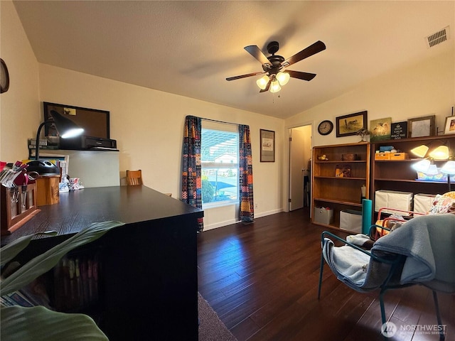 office space featuring dark wood-type flooring, visible vents, baseboards, vaulted ceiling, and a ceiling fan