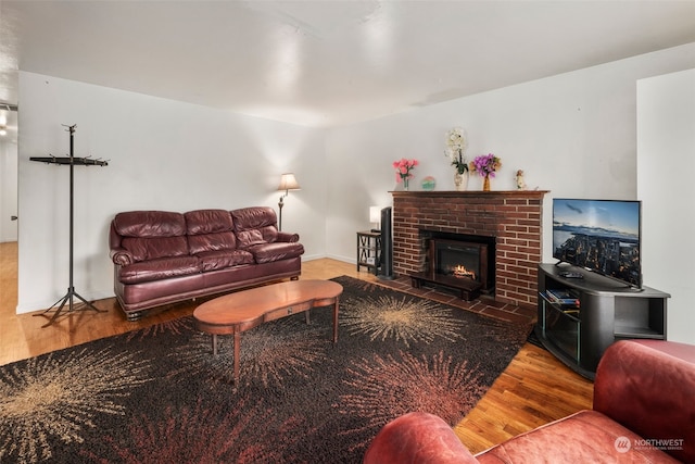 living room with wood-type flooring and a brick fireplace