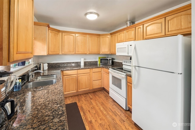 kitchen featuring dark stone countertops, sink, white appliances, and light hardwood / wood-style floors