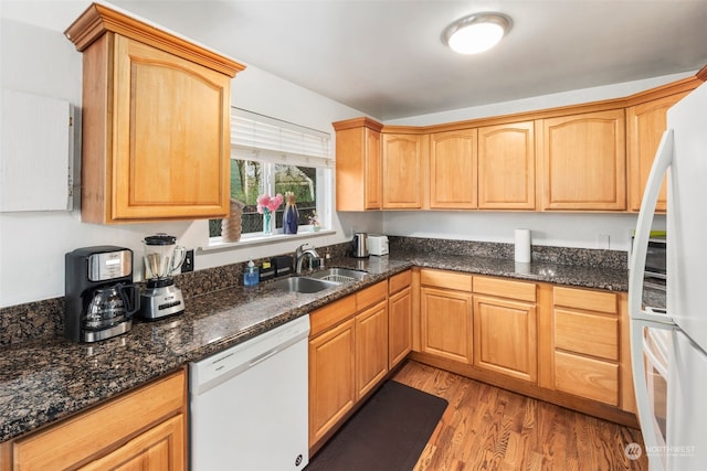 kitchen featuring dark stone countertops, sink, white appliances, and light hardwood / wood-style floors