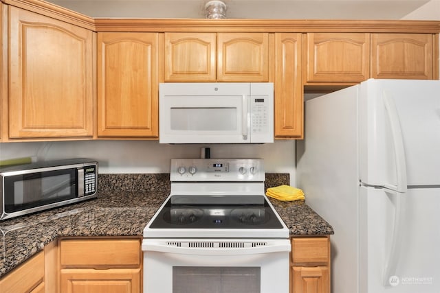 kitchen with dark stone countertops, white appliances, and light brown cabinets