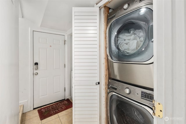 laundry room featuring stacked washer and dryer and light tile patterned floors