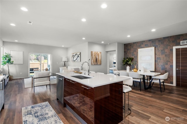 kitchen with dark wood-type flooring, stainless steel dishwasher, sink, and a center island with sink