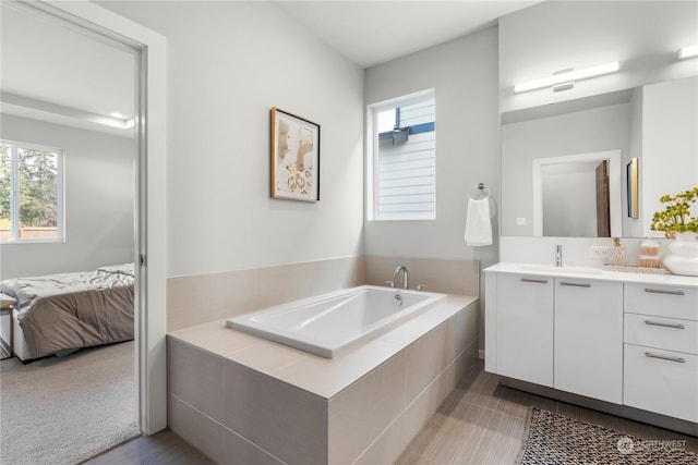 bathroom with vanity and a relaxing tiled tub