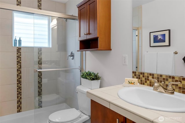 bathroom with vanity, a stall shower, backsplash, and toilet