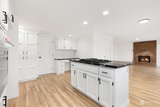 kitchen featuring white cabinetry, a center island, stainless steel gas cooktop, and light wood-type flooring