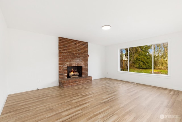 unfurnished living room with a brick fireplace and light wood-type flooring