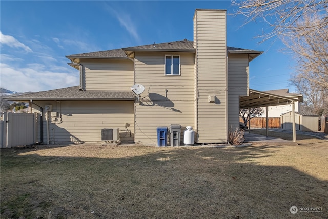 rear view of house featuring central AC unit and a lawn