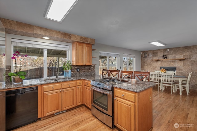 kitchen featuring black dishwasher, sink, dark stone counters, kitchen peninsula, and stainless steel electric range