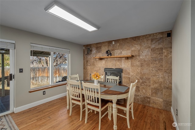 dining space with tile walls, light hardwood / wood-style floors, and a healthy amount of sunlight