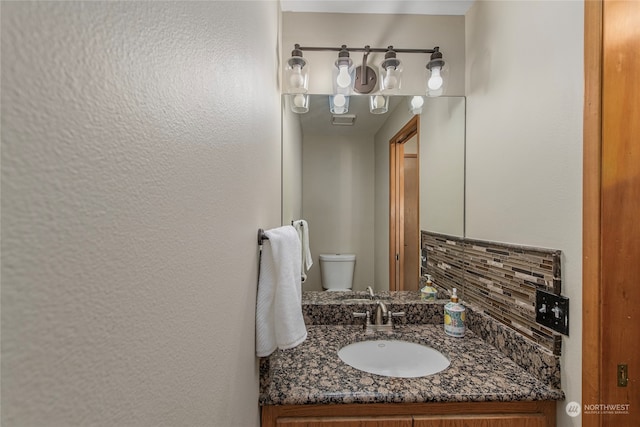 bathroom with vanity, backsplash, and toilet