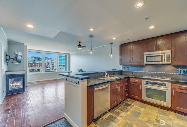 kitchen with appliances with stainless steel finishes, tasteful backsplash, decorative light fixtures, sink, and kitchen peninsula