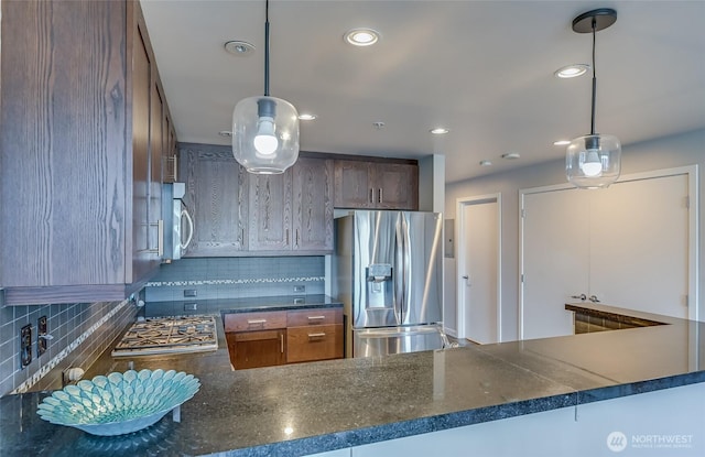 kitchen with decorative backsplash, stainless steel appliances, hanging light fixtures, and kitchen peninsula