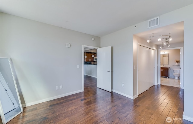 unfurnished bedroom featuring ensuite bath and dark hardwood / wood-style flooring