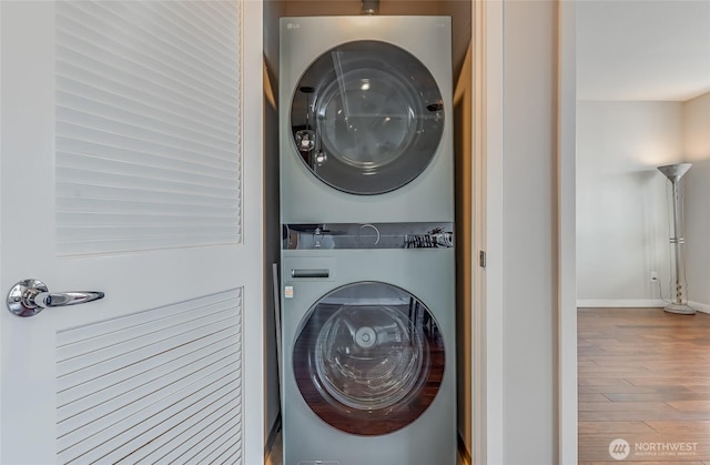 laundry area with hardwood / wood-style floors and stacked washer and clothes dryer