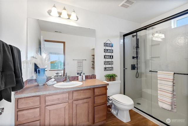 bathroom with vanity, hardwood / wood-style flooring, a shower with shower door, and toilet