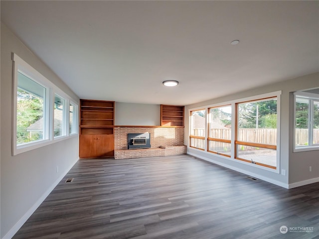 unfurnished living room with dark hardwood / wood-style flooring, a fireplace, and built in features