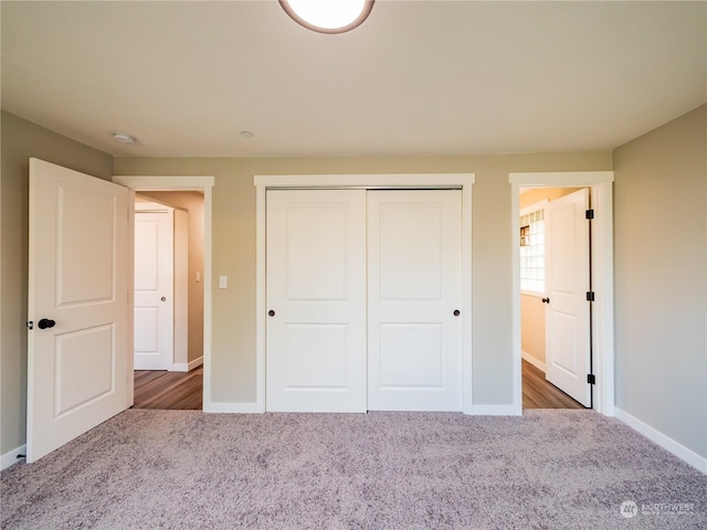 unfurnished bedroom with a closet, carpet flooring, and baseboards