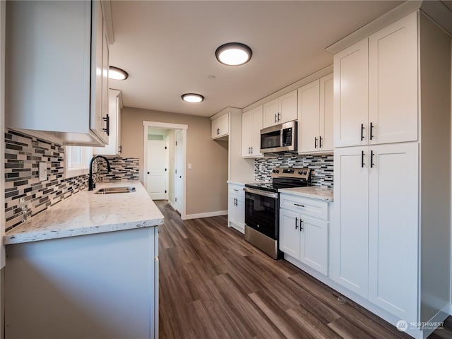 kitchen featuring stainless steel appliances, white cabinetry, a sink, and light stone counters