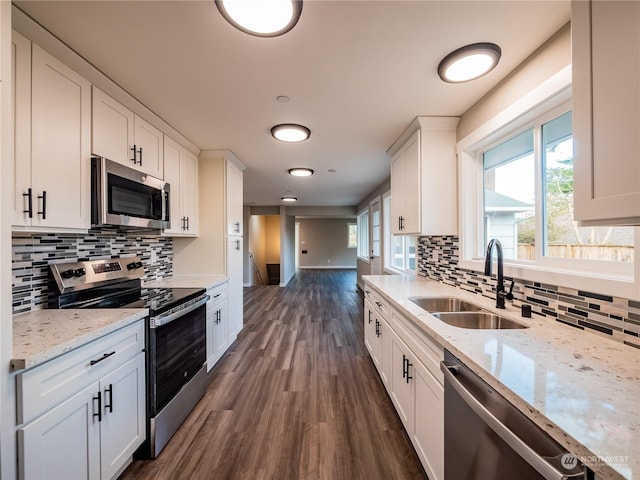 kitchen with sink, white cabinetry, tasteful backsplash, light stone counters, and appliances with stainless steel finishes