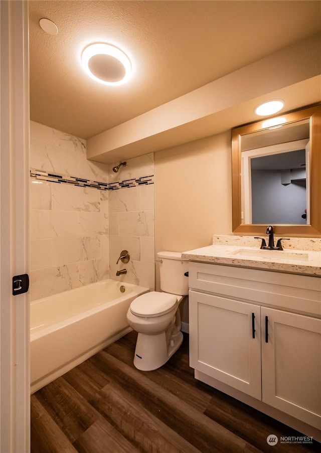 bathroom featuring shower / washtub combination, toilet, a textured ceiling, vanity, and wood finished floors