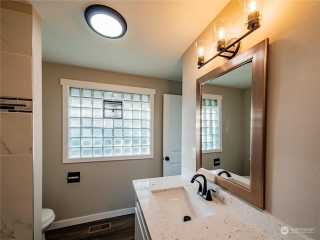 bathroom with visible vents, baseboards, toilet, wood finished floors, and vanity