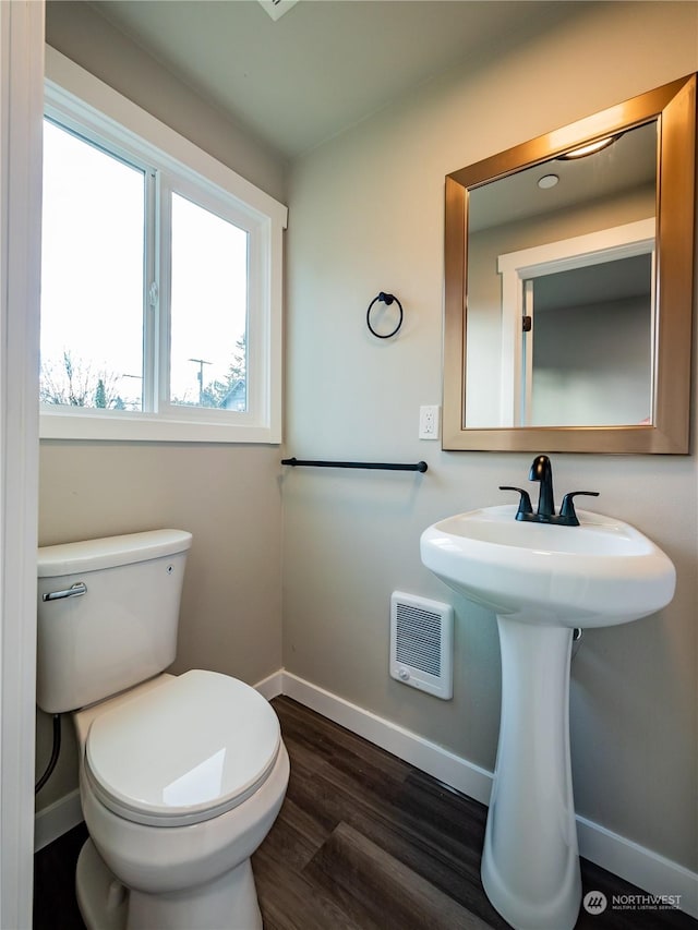 bathroom with toilet, baseboards, and wood finished floors