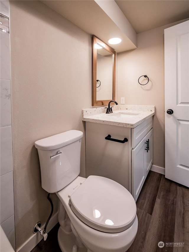 bathroom with toilet, baseboards, wood finished floors, and vanity