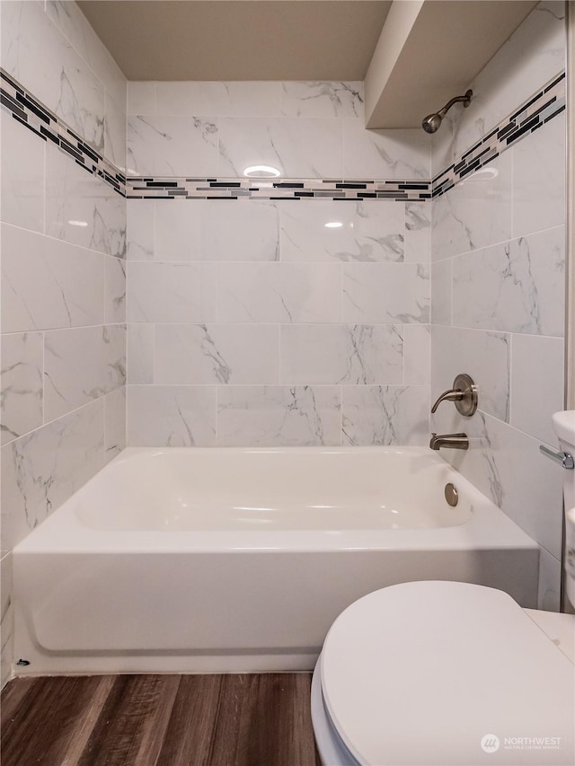 bathroom featuring tiled shower / bath, wood-type flooring, and toilet