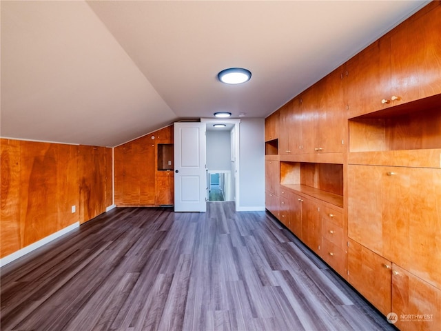 bonus room featuring vaulted ceiling, dark hardwood / wood-style flooring, and wood walls