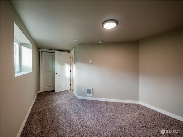 carpeted empty room featuring baseboards